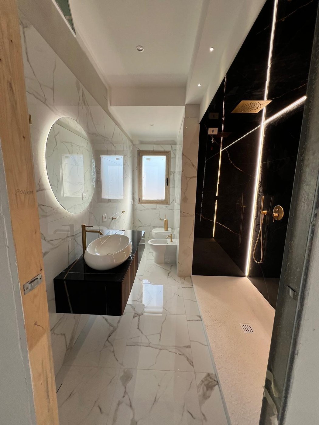 Bagno rifatto con lastre effetto marmo, doccia a filo pavimento e mobile sospeso